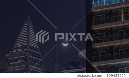 Crescent moon is setting behind skyscrapers in Dubai timelapse. Crescent moon is setting behind skyscrapers in Dubai timelapse. 109485221