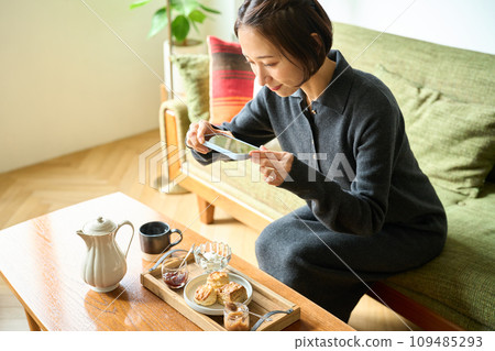 一位女士用智慧型手機拍攝烘焙食品(烤餅)的照片 一位女士用智慧型手機拍攝烘焙食品(烤餅)的照片 109485293