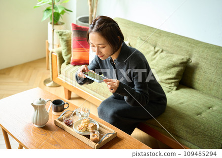 A woman taking a photo of baked goods (scones) with a smartphone A woman taking a photo of baked goods (scones) with a smartphone 109485294