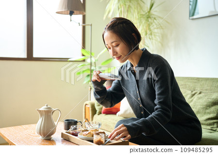 A woman taking a photo of baked goods (scones) with a smartphone 109485295