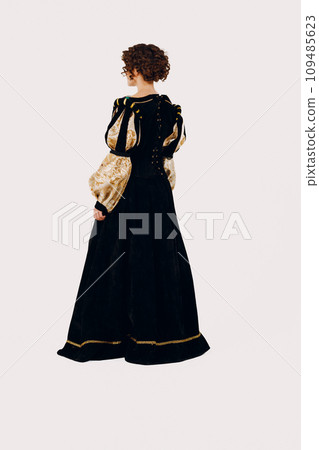 Portrait of a young aristocratic woman dressed in a medieval dress on white background. Back view Portrait of a young aristocratic woman dressed in a medieval dress on white background. Back view 109485623