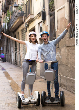 Young couple guy and girl walking on segway in streets of european city 109486546