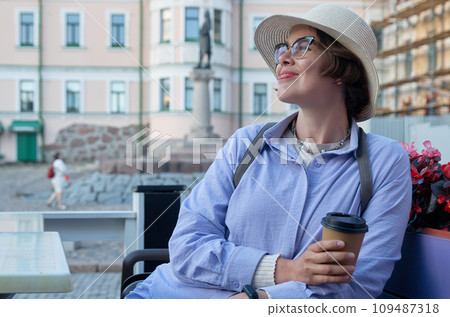 A girl drinks coffee from a paper cup in a coffee shop on the street of an ancient city 109487318