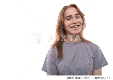 Portrait of a modest teenager girl with braces in a gray T-shirt on a white background Portrait of a modest teenager girl with braces in a gray T-shirt on a white background 109488255