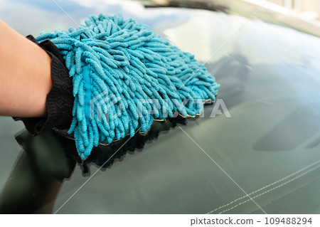 Car wash and self-service concept. A man washes the car windshield with a large blue washcloth. 109488294
