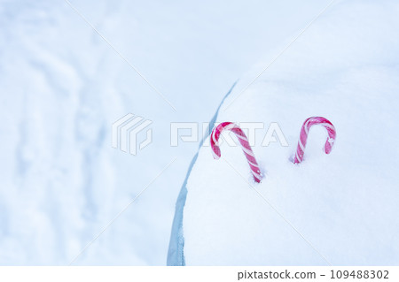 Two lollipops sticking out of a snowdrift against the backdrop of a blurry winter landscape. Place for inscription. Two lollipops sticking out of a snowdrift against the backdrop of a blurry winter landscape. Place for inscription. 109488302