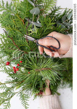 The concept of preparation for Christmas and New Year, hobby, handwork. The process of making a Christmas wreath from chopped branches of various conifers. 109488305