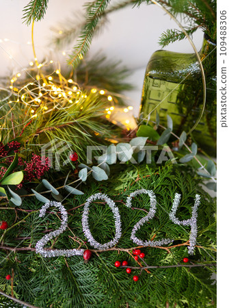 2024 new year green background from live leaves and branches. Seasonal packaging and New Year's paraphernalia. New Year's composition, a ready-made opening. 2024 new year green background from live leaves and branches. Seasonal packaging and New Year's paraphernalia. New Year's composition, a ready-made opening. 109488306