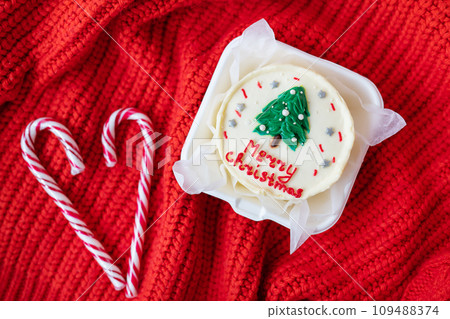 Christmas cupcake with a candy cane heart on a red knitted background. Merry christmas cake inscription. 109488374