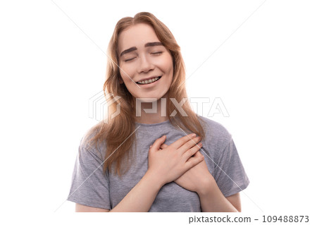 Kind modest bright blond teenager girl with braces in a gray T-shirt Kind modest bright blond teenager girl with braces in a gray T-shirt 109488873