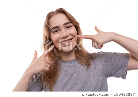 Smiling teenage girl with braces in a gray T-shirt on a white background 109488887