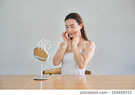 A woman in her 30s taking care of her skin by massaging her face 109489555