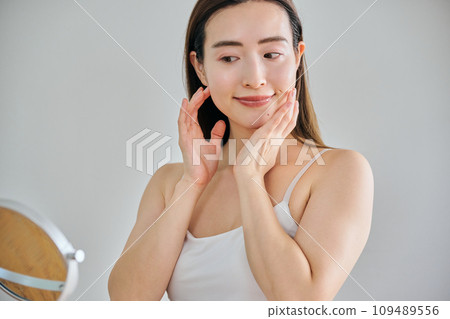 A woman in her 30s taking care of her skin by massaging her face 109489556