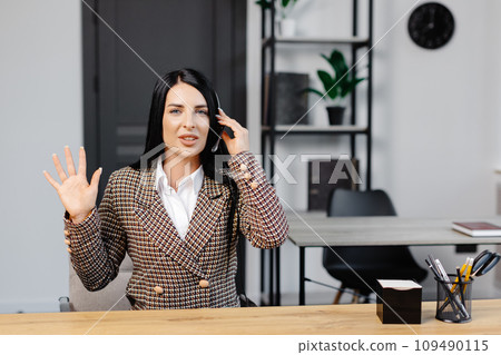 Call center agent with headset working on support hotline in modern office. Video conference. Call center agent with headset working on support hotline in modern office. Video conference. 109490115