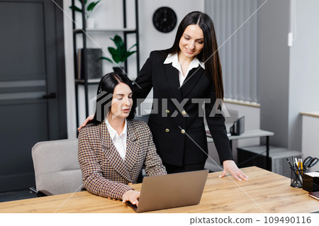 Call center agent with headset working on support hotline in modern office. Two young attractive women are working in the office Call center agent with headset working on support hotline in modern office. Two young attractive women are working in the office 109490116