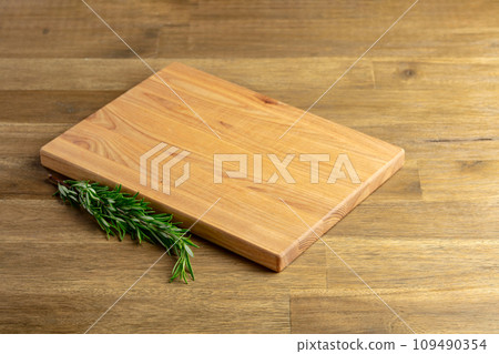 Cutting board and rosemary on an old wooden table. Cutting board and rosemary on an old wooden table. 109490354