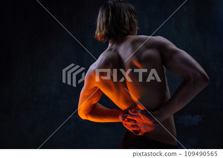 Relief, muscular, athletic male back. Shirtless model with fit body posing against dark studio background 109490565