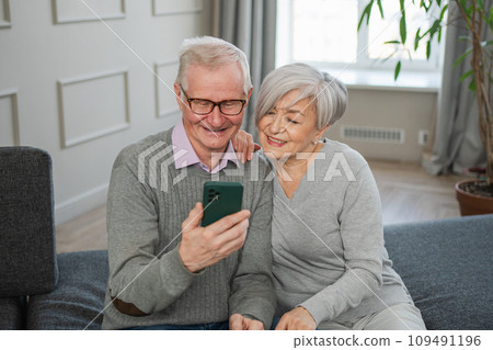 Video call. Happy senior couple woman man with smartphone having video call. Mature old grandmother grandfather talking speaking online. Older generation modern tech usage. Virtual meeting online chat Video call. Happy senior couple woman man with smartphone having video call. Mature old grandmother grandfather talking speaking online. Older generation modern tech usage. Virtual meeting online chat 109491196