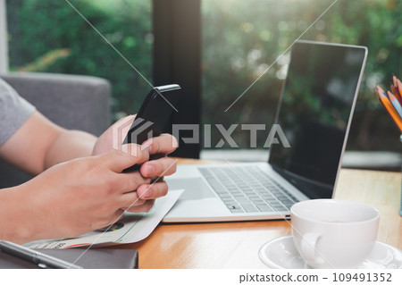 A man holding a smartphone in one corner of the home office. A man holding a smartphone in one corner of the home office. 109491352