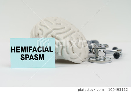 On a white surface next to the brain there is a stethoscope and stickers with the inscription - Hemifacial spasm 109493112