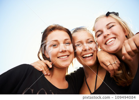 Friends, portrait and women hug outdoor for travel, bond and having fun on vacation, break or trip. Face, smile and group or people embrace outside for reunion, weekend or holiday hangout on blue sky 109494084