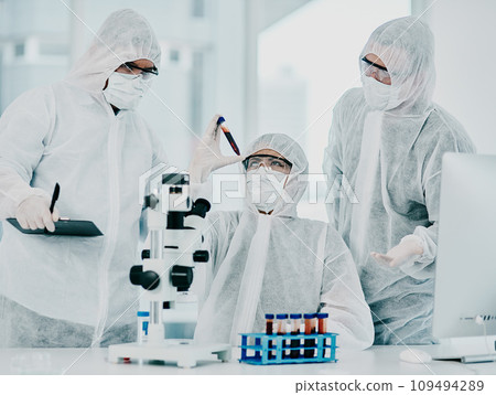 Group of doctors and scientists conducting medical research on viruses dressed in hazmat suits, for coronavirus cure in the lab. Researchers conducting experiments and examining test tube Group of doctors and scientists conducting medical research on viruses dressed in hazmat suits, for coronavirus cure in the lab. Researchers conducting experiments and examining test tube 109494289