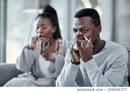Flu, cold or sick couple with covid coughing, sneezing and blowing their nose with a tissue while in isolation together at home in winter. Young husband and wife with a bad seasonal fever illness 109494377