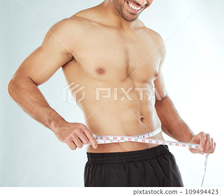 Measuring tape, stomach and fitness man in studio with weight loss, progress or bmi control on white background. Body, wellness and male model with waist measurement for diet, detox or sixpack check 109494423