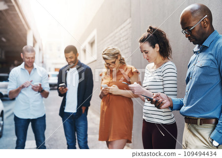 Business people reading text on phone, checking notifications and typing messages online during a break at work. Group of diverse colleagues scrolling on the internet, browsing app and networking Business people reading text on phone, checking notifications and typing messages online during a break at work. Group of diverse colleagues scrolling on the internet, browsing app and networking 109494434