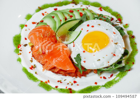 Poached eggs on top of smashed avocado on sourdough toast with smoked salmon. Healthy breakfast with plate on table. Top view. Copy space to right Poached eggs on top of smashed avocado on sourdough toast with smoked salmon. Healthy breakfast with plate on table. Top view. Copy space to right 109494587