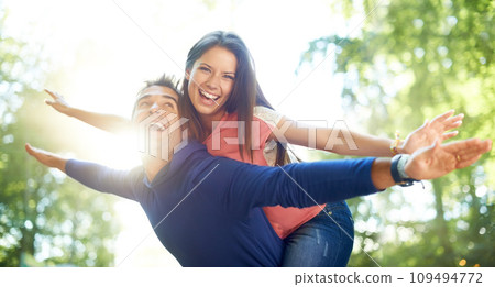 Outdoor, piggy back and couple with love, nature and summer with lens flare, marriage and adventure. Portrait, man carrying woman and woods for fun, playing and journey with relationship and romance 109494772