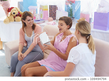 Women, baby shower and opening gift in home, happy and surprised with present and grateful. Pregnant lady, smile and excited for pregnancy, motherhood and celebrating child with friends in house Women, baby shower and opening gift in home, happy and surprised with present and grateful. Pregnant lady, smile and excited for pregnancy, motherhood and celebrating child with friends in house 109494794