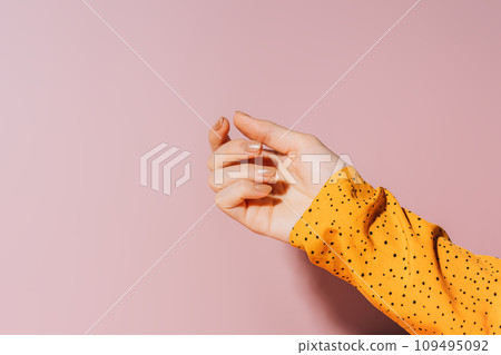 Empty female hand with painted nails in gold glittering color against pink background, manicure 109495092
