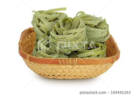 Raw tagliatelle green pasta with spinach in a wicker basket isolated on white background Raw tagliatelle green pasta with spinach in a wicker basket isolated on white background 109495263
