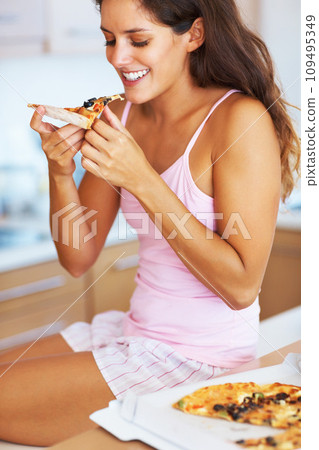 Smile, eating and young woman with pizza for dinner, supper or lunch on weekend at home. Happy, meal and female person from Canada in pajamas enjoying fast food in kitchen at modern apartment 109495349
