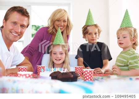 Birthday, party and a family in their home together for the celebration of a milestone with children. Smile, love or a happy mother, father and sibling kids in the living room for an event with cake Birthday, party and a family in their home together for the celebration of a milestone with children. Smile, love or a happy mother, father and sibling kids in the living room for an event with cake 109495405