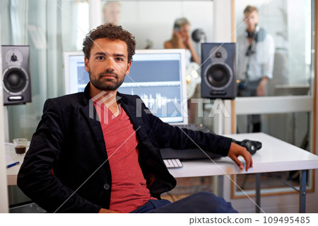Portrait, media and a man producer in a recording studio mixing audio with a sound desk. Computer, tech or music with a serious young DJ or engineer creating a track for production or entertainment 109495485
