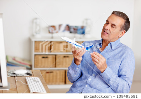 Mature man, thinking and toy plane for travel, vacation and holiday planning with a smile at home. Happy, airplane model and retirement of a male person with confidence from trip and air traveling Mature man, thinking and toy plane for travel, vacation and holiday planning with a smile at home. Happy, airplane model and retirement of a male person with confidence from trip and air traveling 109495681