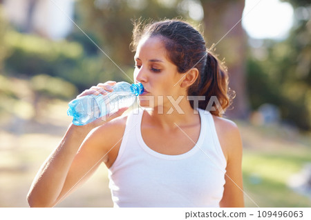 Young woman, drinking water and workout in nature for exercise, running break and health, energy or fitness. Tired and thirsty runner or sports person with bottle for training outdoor, park or forest Young woman, drinking water and workout in nature for exercise, running break and health, energy or fitness. Tired and thirsty runner or sports person with bottle for training outdoor, park or forest 109496063