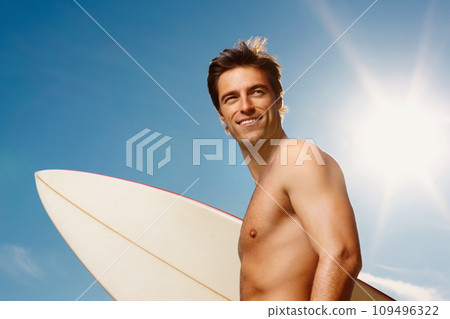 Man, happy or shirtless with surfboard for summer workout, muscle or confident on vacation. Model, smile and fitness with natural glow of sport, cardio exercise and sunshine holiday by sky background Man, happy or shirtless with surfboard for summer workout, muscle or confident on vacation. Model, smile and fitness with natural glow of sport, cardio exercise and sunshine holiday by sky background 109496322