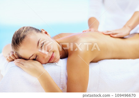 Woman, relax and massage for back with spa therapist for wellness, holistic therapy or cosmetic care at holiday resort. Beauty salon, skincare and or calm client rest for treatment, peace or vacation 109496670