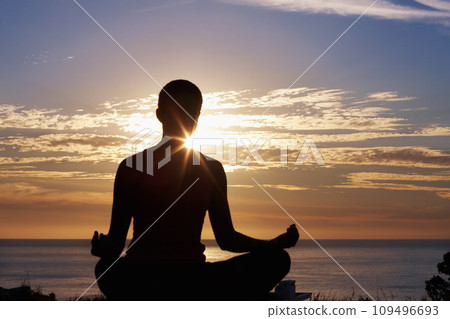 Person, meditation and yoga in beach sunset for zen fitness, calm exercise and mindfulness or holistic wellness in silhouette. Back and nature with lotus hands, outdoor peace and mental health by sea 109496693