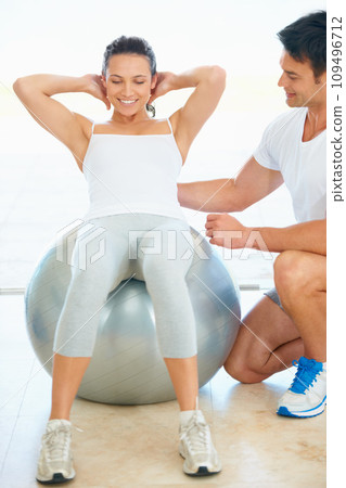 Woman, exercise and fitness with personal trainer, ball and workout in gym for health and wellness. Cardio, training and person with coach for core, crunches and help in pilates with happiness Woman, exercise and fitness with personal trainer, ball and workout in gym for health and wellness. Cardio, training and person with coach for core, crunches and help in pilates with happiness 109496712