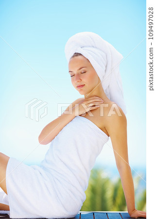 Peace, woman and spa towel outdoor with wellness, skincare and health treatment with blue sky. Luxury, rest and zen of calm female person on vacation with body care and hotel for vacation and travel 109497028