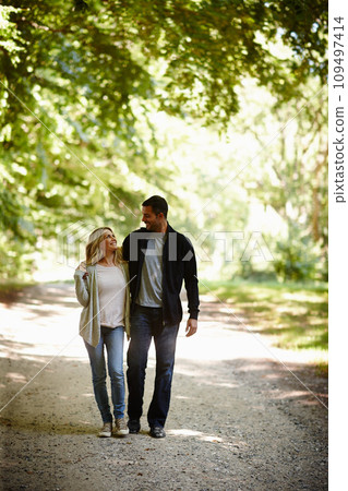 Always by each others side. Full length shot of a young couple walking arm in arm in a park. 109497414