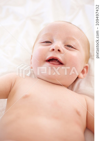 Happy baby on bed, funny and top view portrait of young child in development, excited or relax at home. Face, above and infant kid laugh in nursery, rest in bedroom or healthy body, cute or adorable 109497432