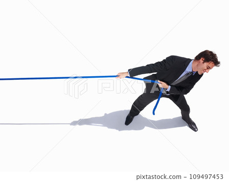 Businessman, frustrated and tug of war by white background, career challenge and industry competition. Young person, mental health and professional worker with rope, top view and job battle in studio 109497453