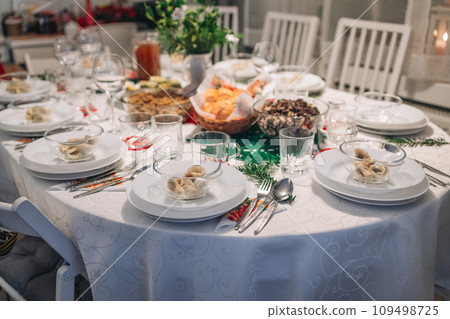 Christmas Eve's red borscht soup with mushroom filled ravioli and beet chips and sauerkraut with mushrooms on festive table. Polish Wigilia. Christmas Eve's red borscht soup with mushroom filled ravioli and beet chips and sauerkraut with mushrooms on festive table. Polish Wigilia. 109498725