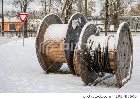 Wooden coil for wires. Empty cable reel. Winter landscape Wooden coil for wires. Empty cable reel. Winter landscape 109499606