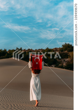 A beautiful dark-haired woman holds a Turkish flag in her hands, rear view. A woman is traveling in Turkey. A tourist on the background of Patara beach in Turkey. Vacation in Turkey. Turkish flag A beautiful dark-haired woman holds a Turkish flag in her hands, rear view. A woman is traveling in Turkey. A tourist on the background of Patara beach in Turkey. Vacation in Turkey. Turkish flag 109499670